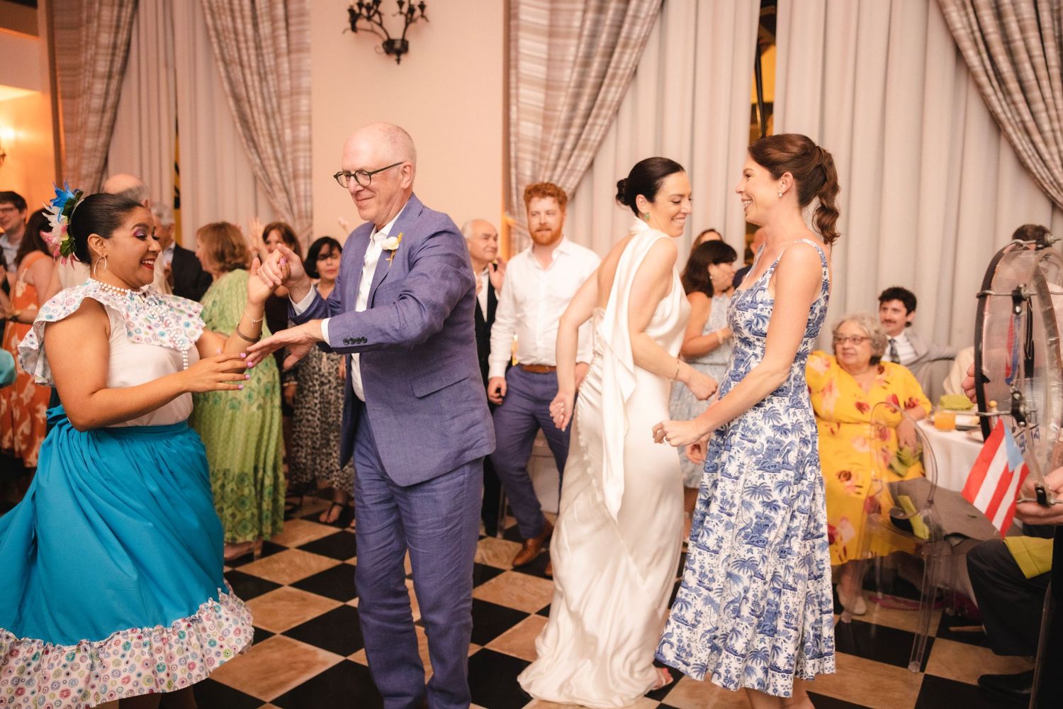 Wedding guests dance and celebrate during a lively reception party at an indoor venue.