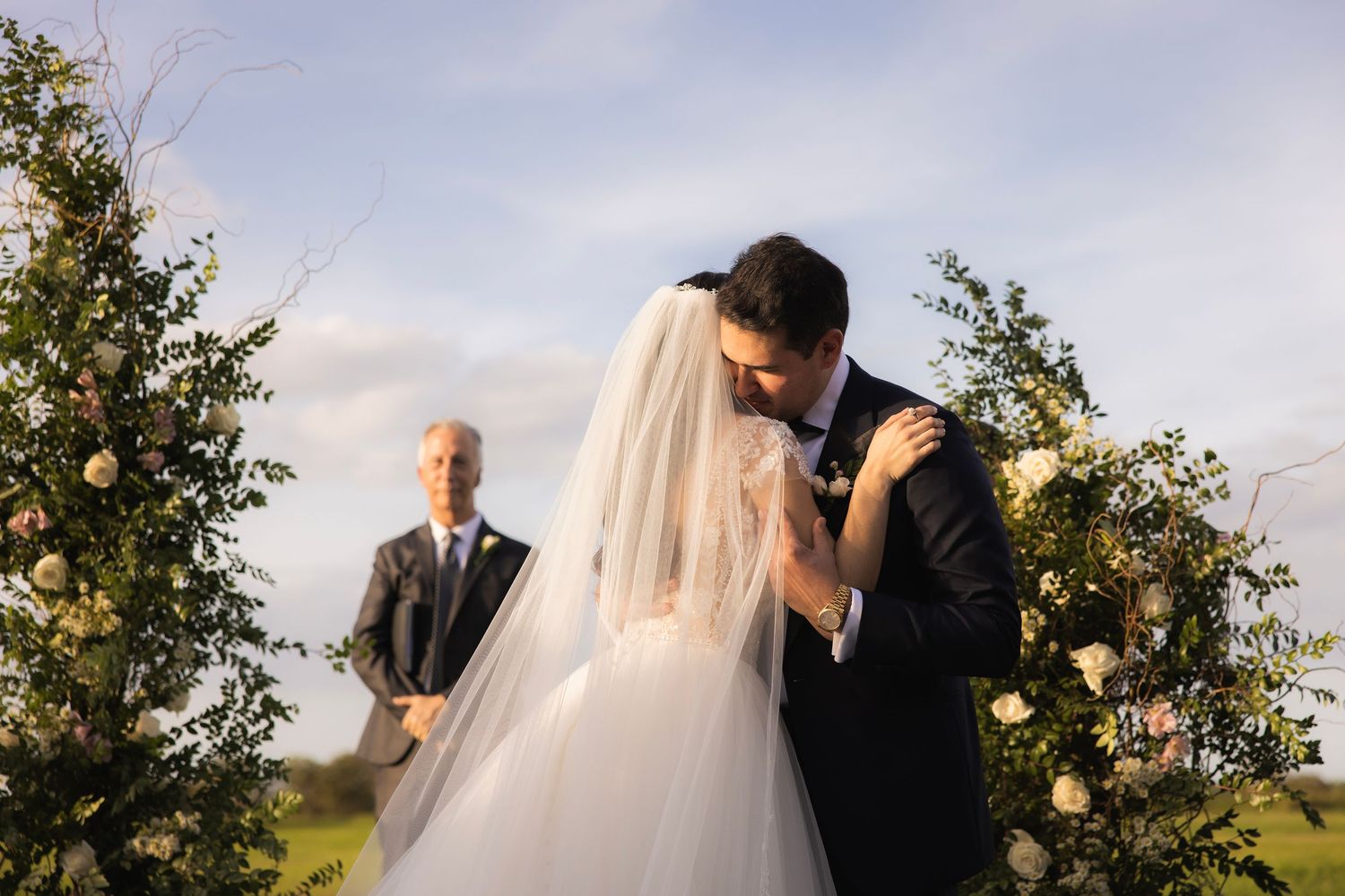 Newlyweds share a tender moment during their outdoor garden ceremony at sunset.