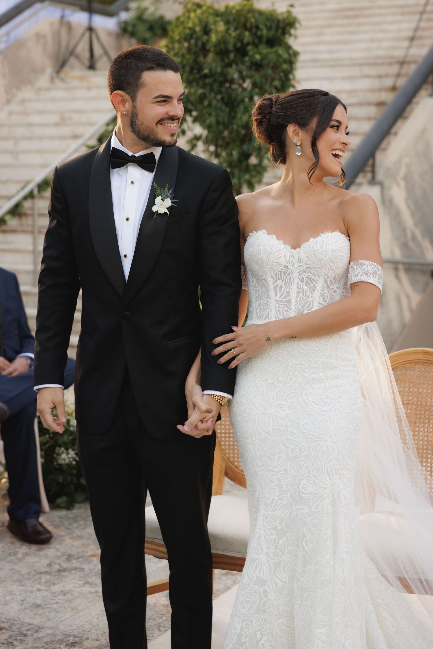 A newlywed couple shares a joyful moment in elegant wedding attire at their outdoor ceremony.