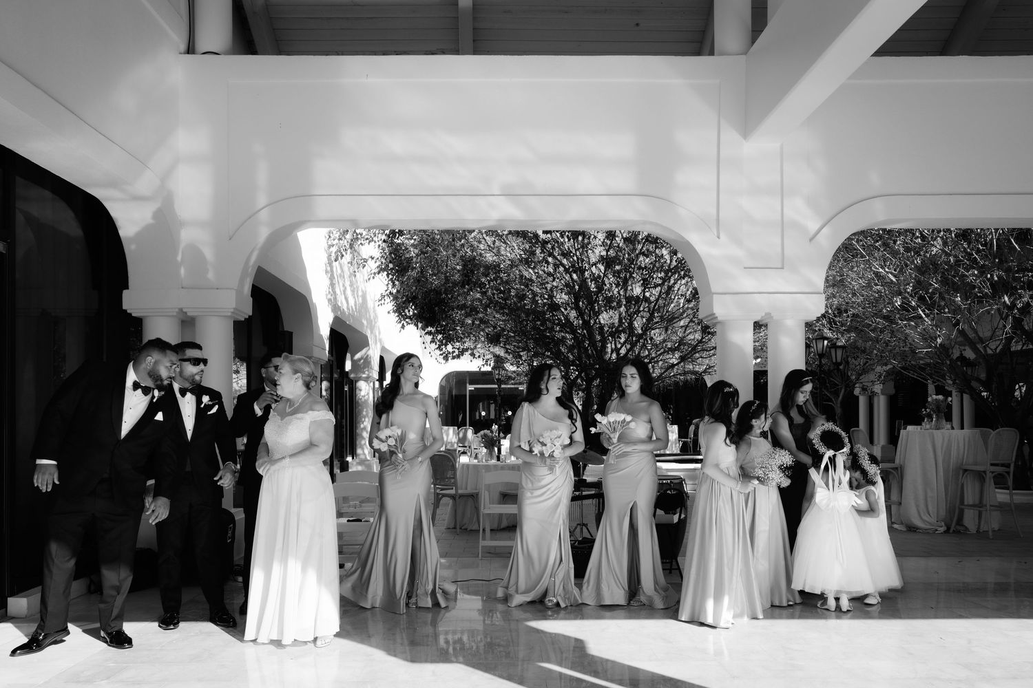 A black and white photo strip showing multiple wedding party group shots in formal attire and graceful poses.