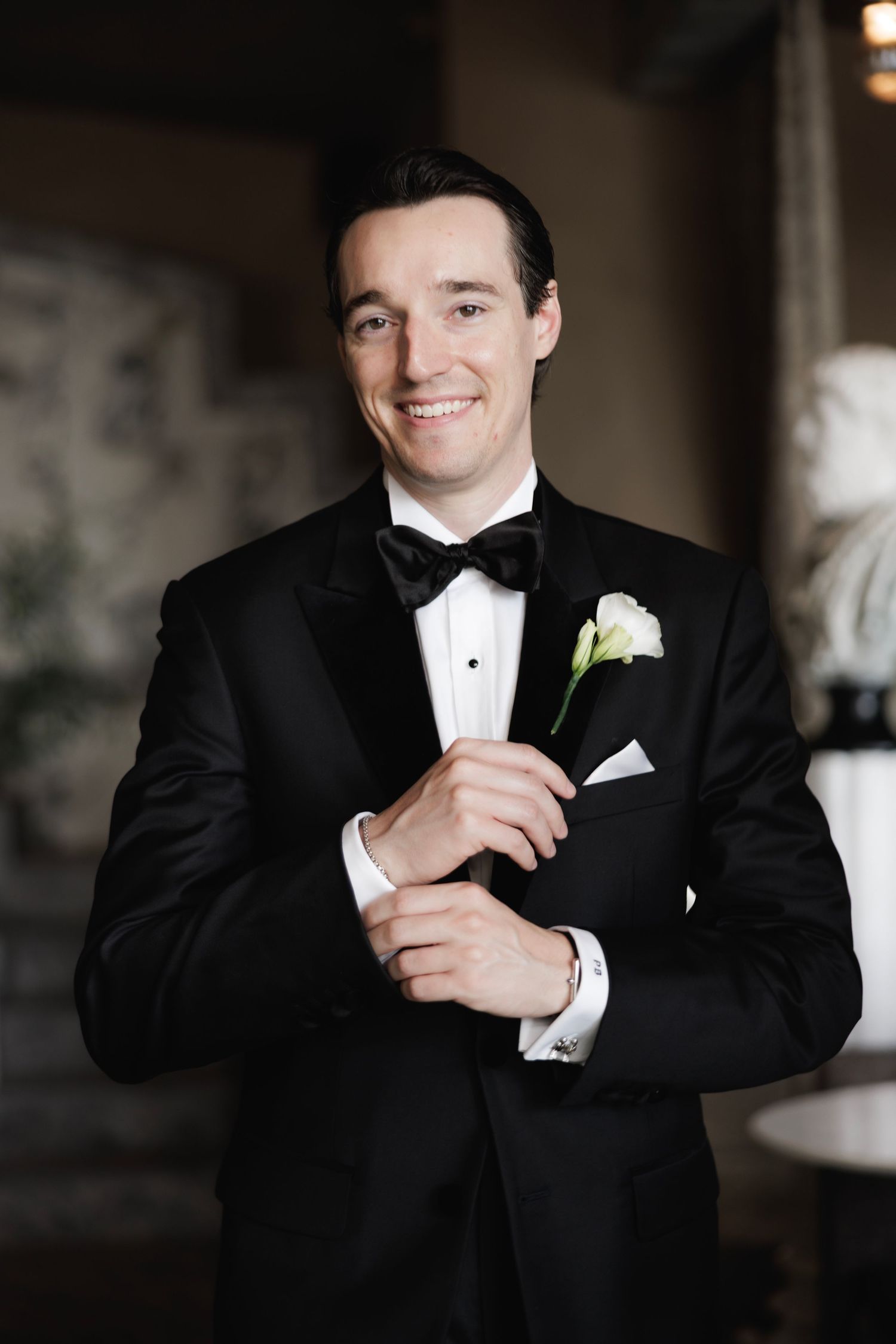 A series of wedding portraits showing a groom in a black tuxedo against a dark background with soft lighting.