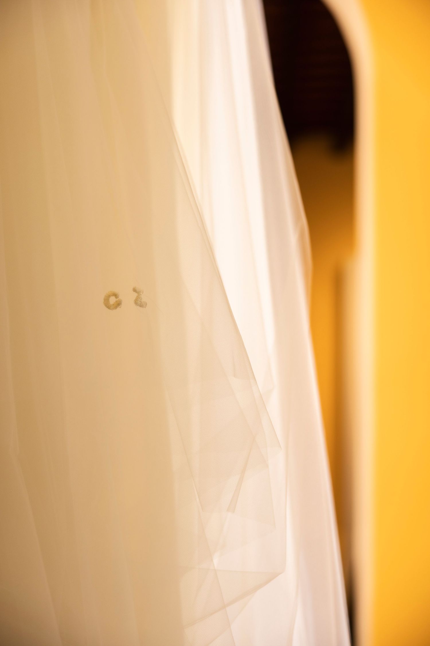 Close-up detail of delicate white tulle and fabric with soft golden lighting.