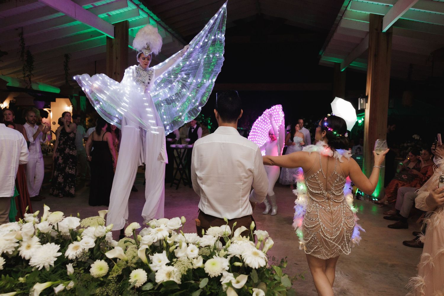 Event space decorated with white flowers and purple lighting for a celebration.