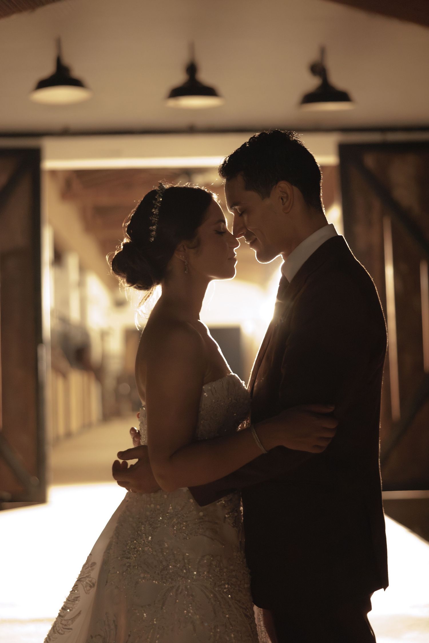 A romantic silhouette of newlyweds sharing an intimate moment under industrial pendant lights.