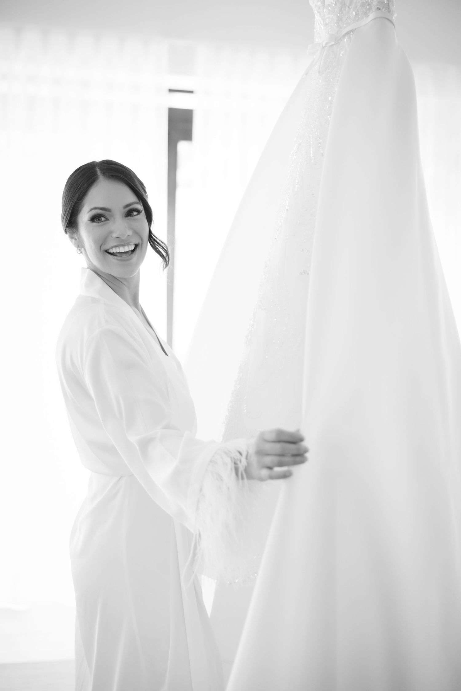 Bride and bridesmaids in white robes share joyful moments during wedding preparations.