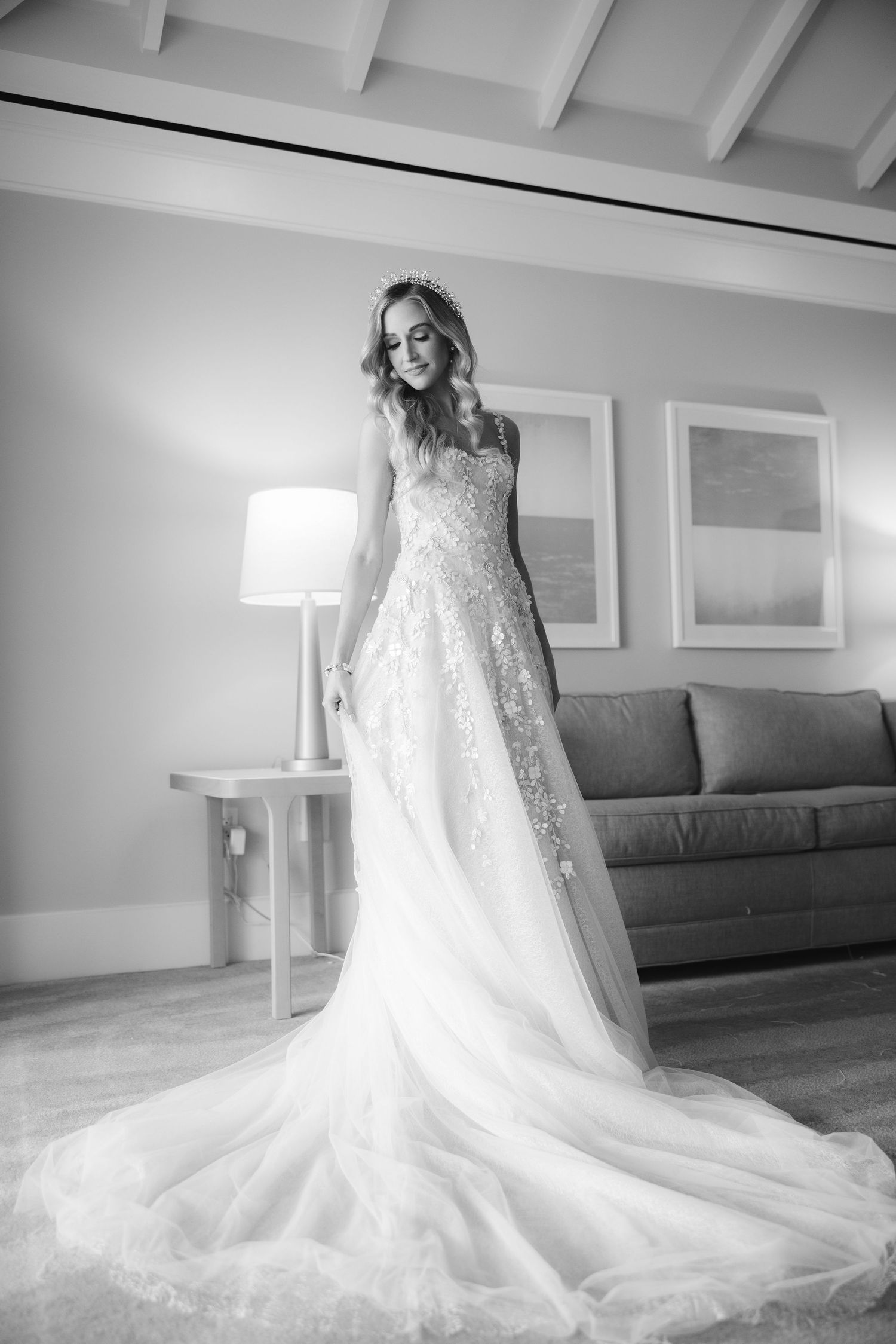 An elegant white wedding gown with intricate lace details and dramatic cathedral-length train displayed on hardwood flooring.