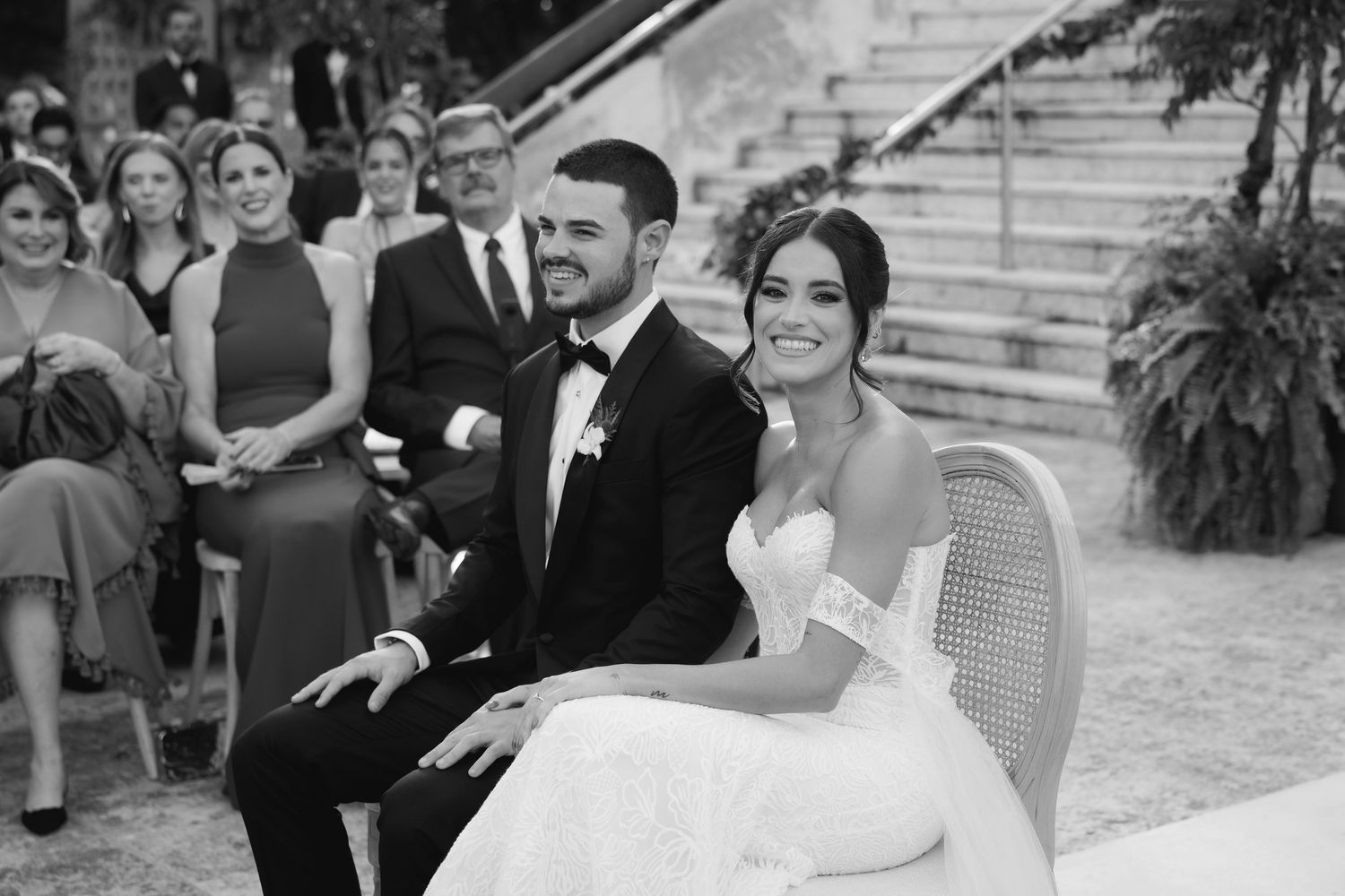 Wedding guests gather on outdoor steps for group photos while celebrating during an elegant ceremony.