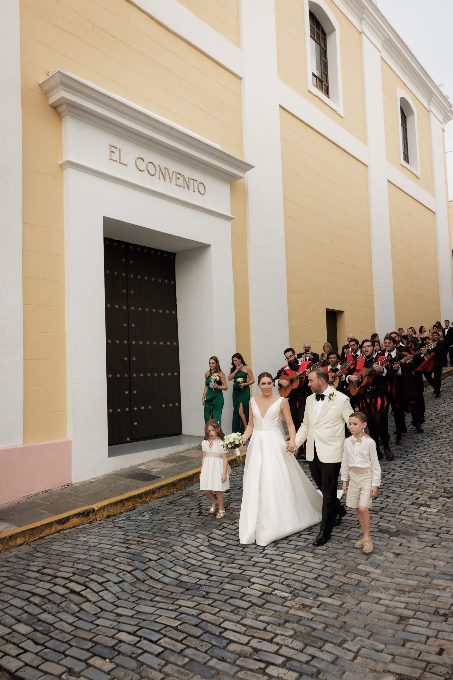 Wedding party walking along a cobblestone street outside El Convento building in Old San Juan.