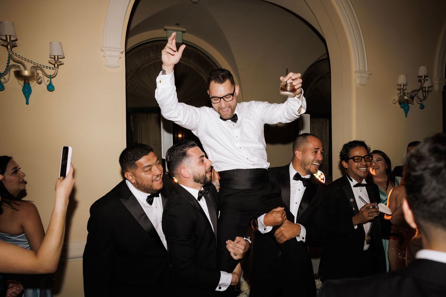 Party guests enjoying themselves with enthusiastic dancing at an elegant indoor venue.