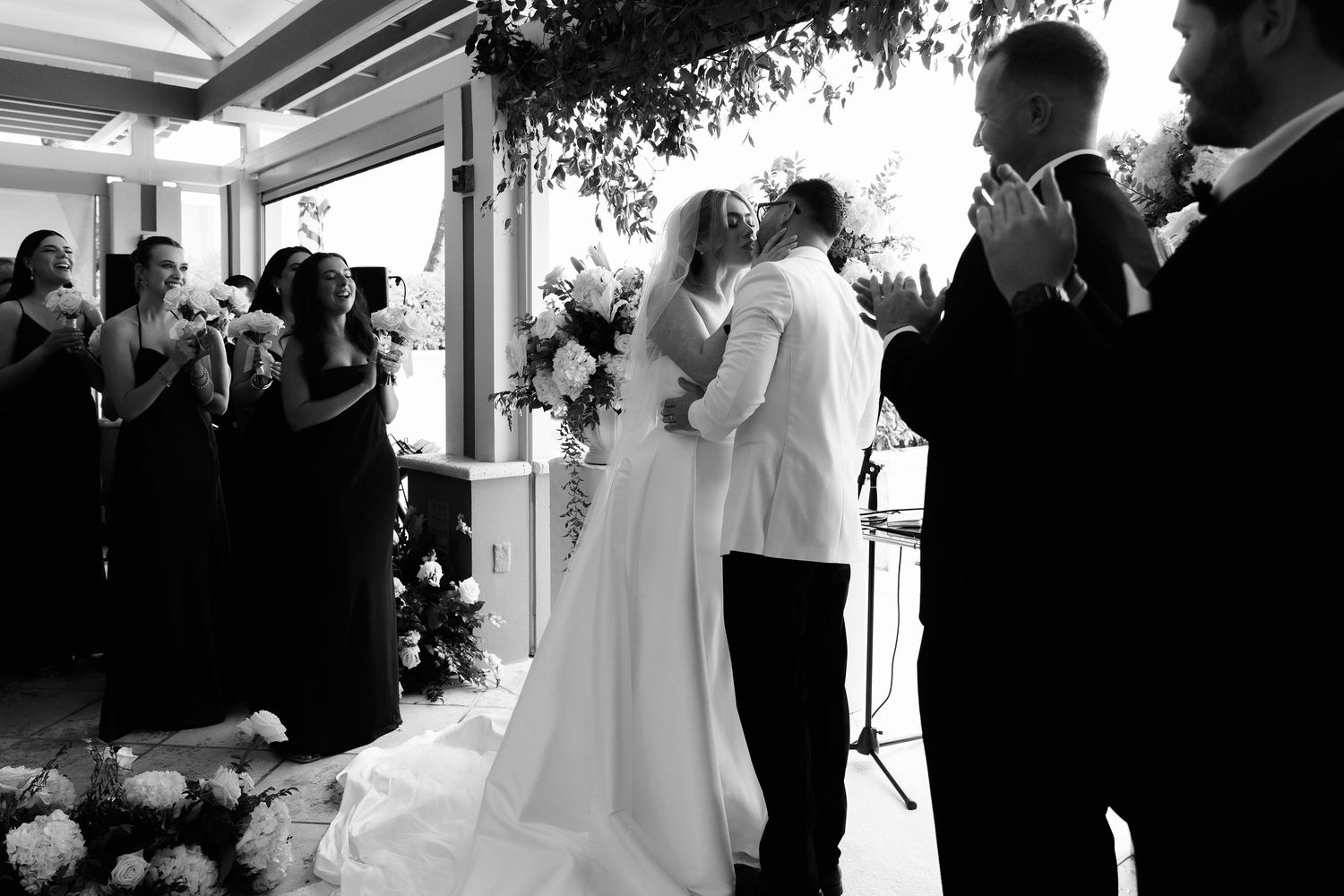 Monochrome images showing an emotional wedding ceremony with couple and guests in an indoor venue.