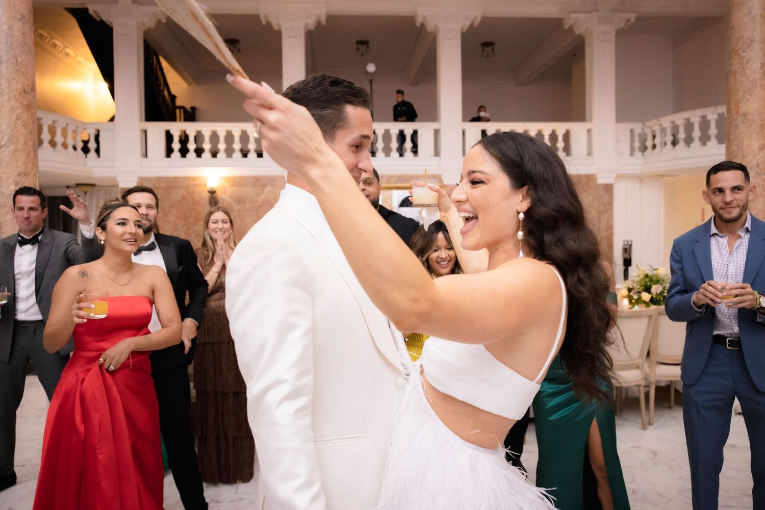 A couple shares their first dance at an elegant wedding reception while guests watch from the sidelines.