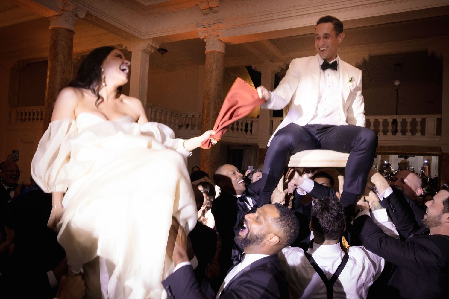Wedding celebration in an ornate ballroom with dancing guests.
