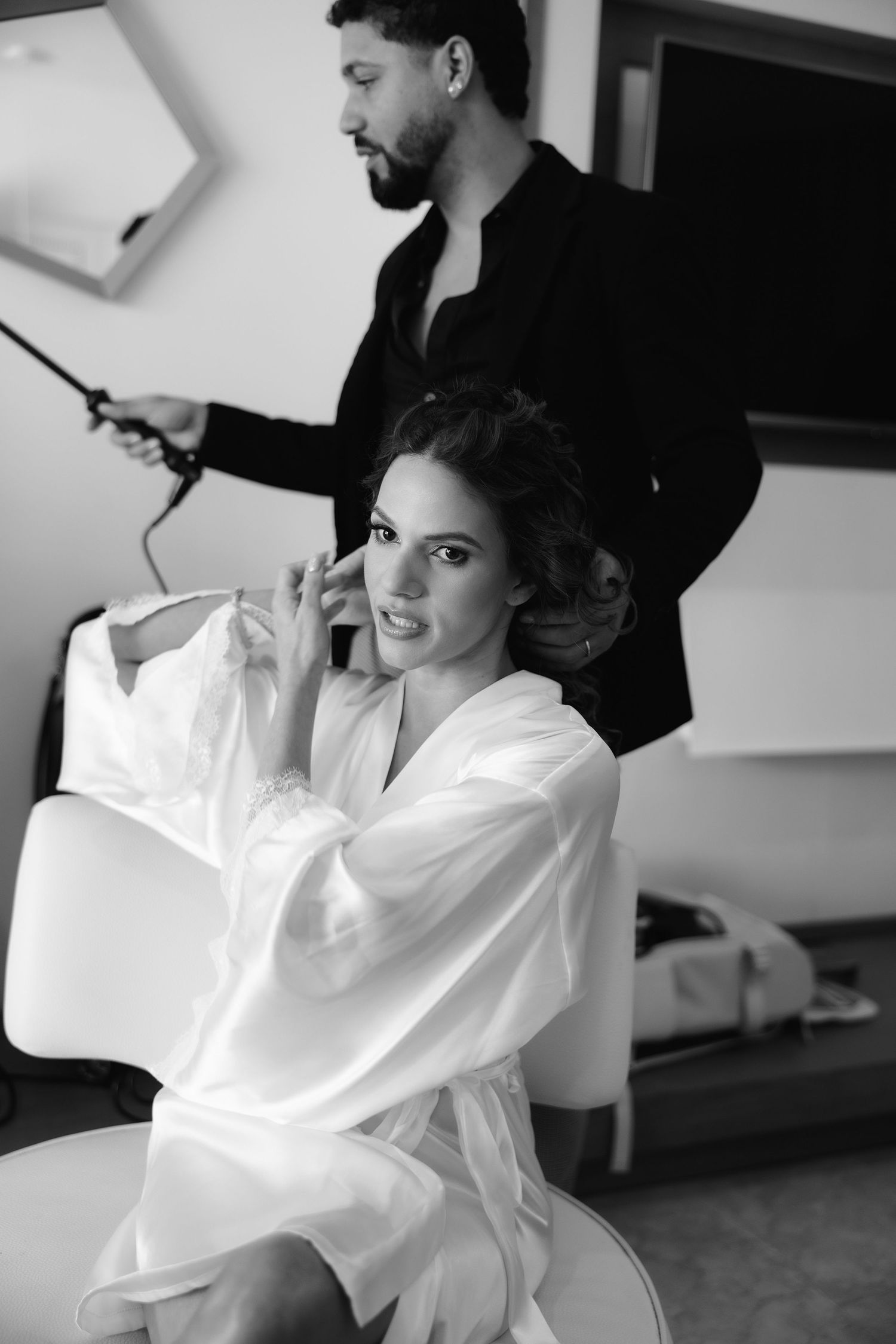 Black and white photos show a woman in white robe getting her hair styled in consecutive shots.