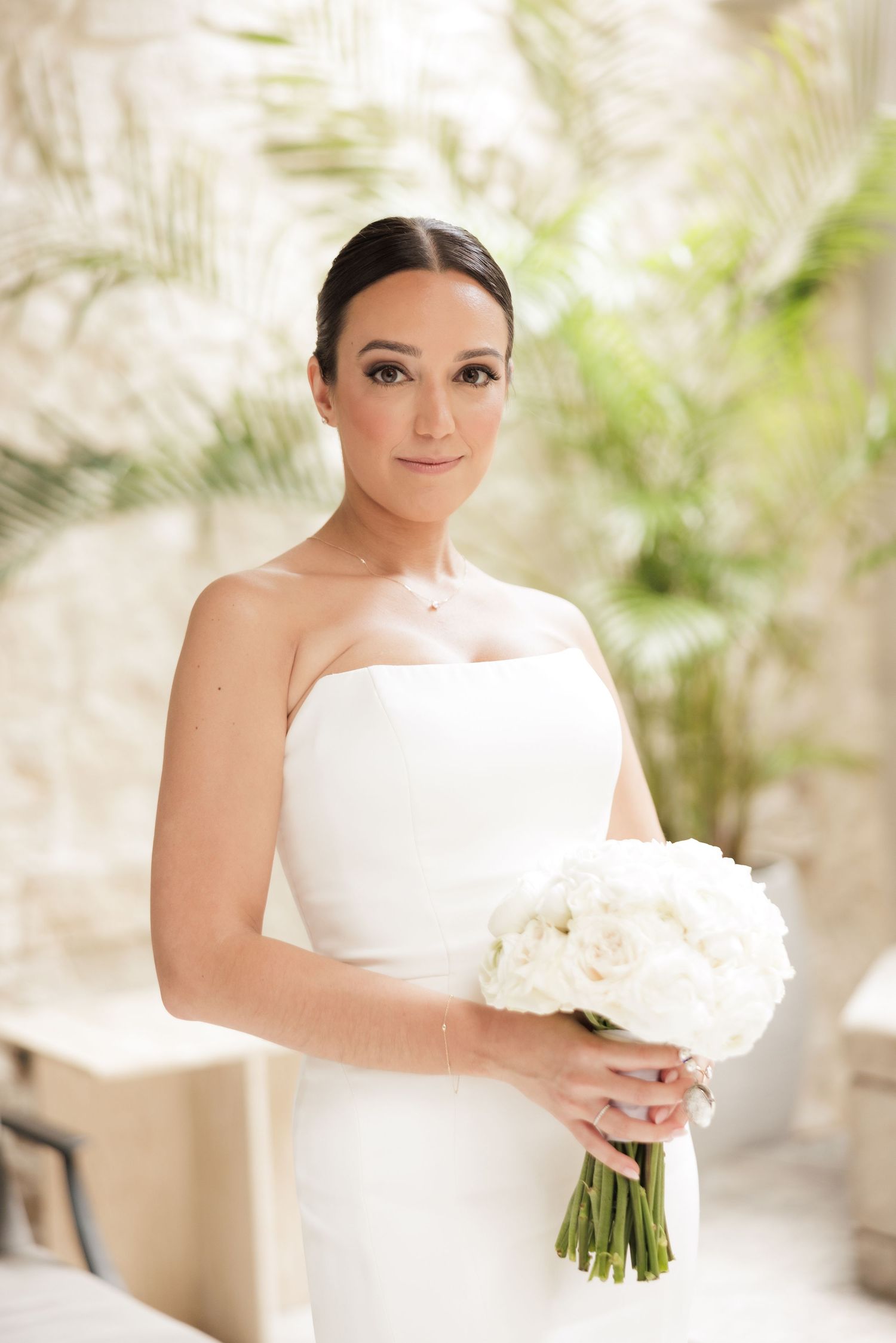 Classic white wedding dress with bouquet photographed in elegant interior setting.