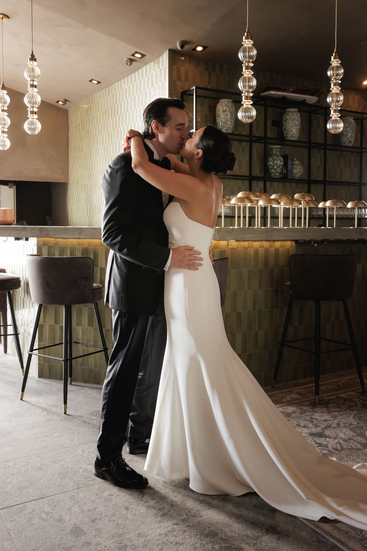 A romantic first dance sequence showing a couple in formal wedding attire dancing in an elegant venue with hanging lights.