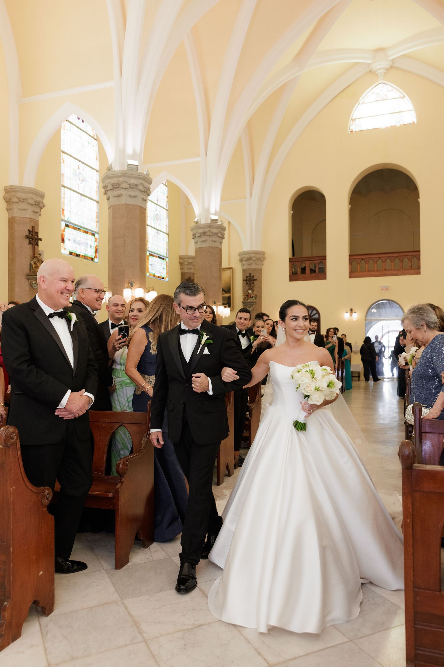 Wedding ceremony in a grand church with white columns and arched ceilings.