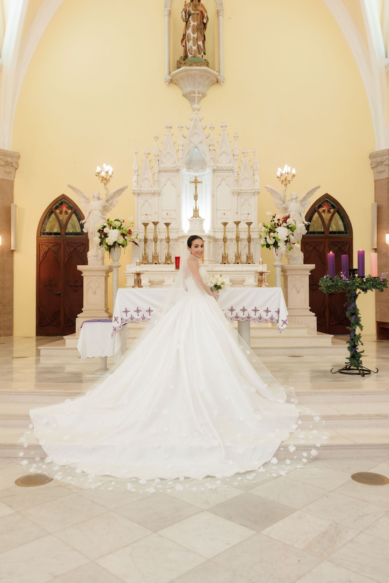Stunning bridal portrait in cathedral with long train spread across marble floor.