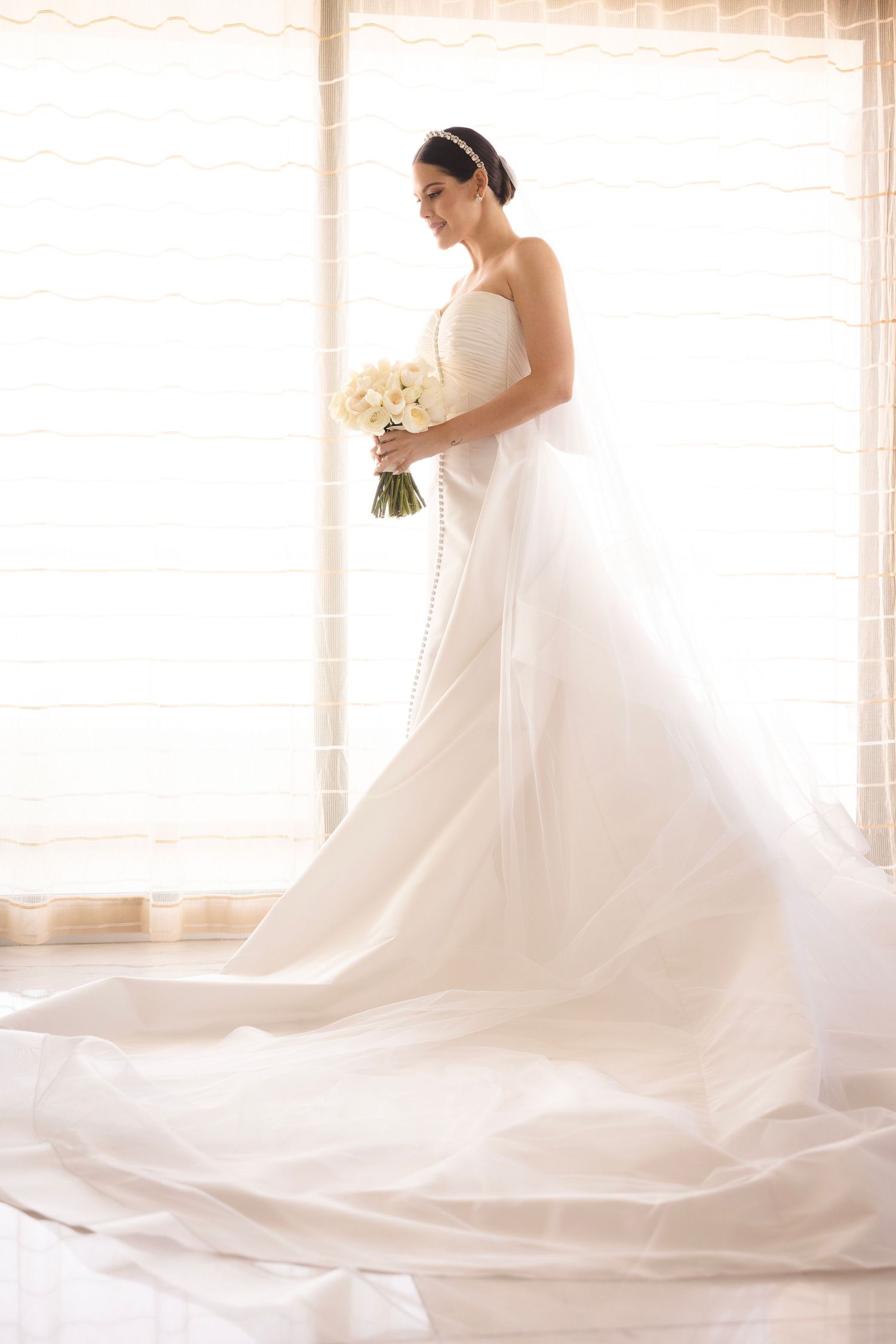 Ethereal bridal portrait series showing flowing white wedding gown with long train in soft natural window light.