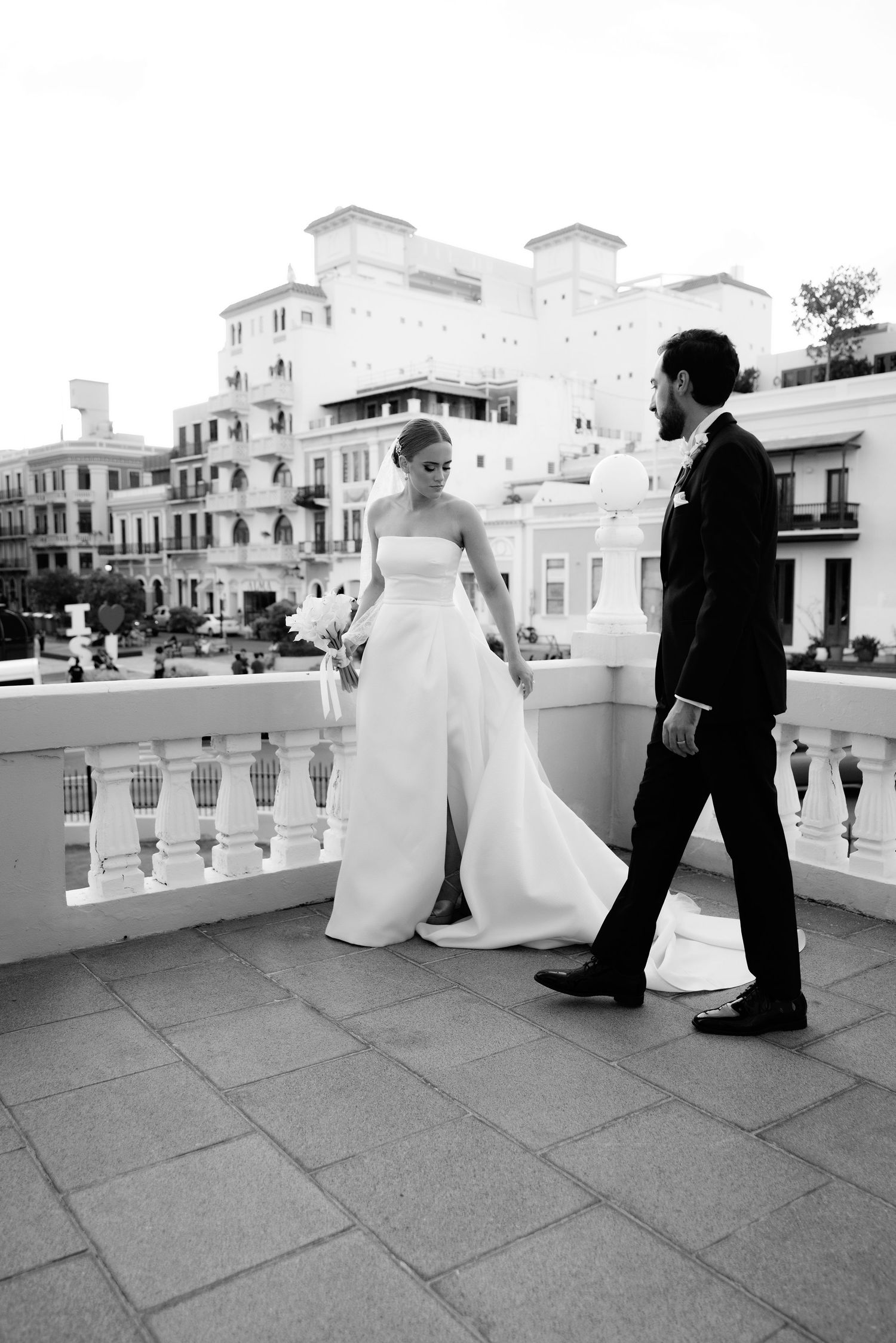 A series of black and white wedding photos showing a couple sitting on a stone balcony with classic architecture in the background.