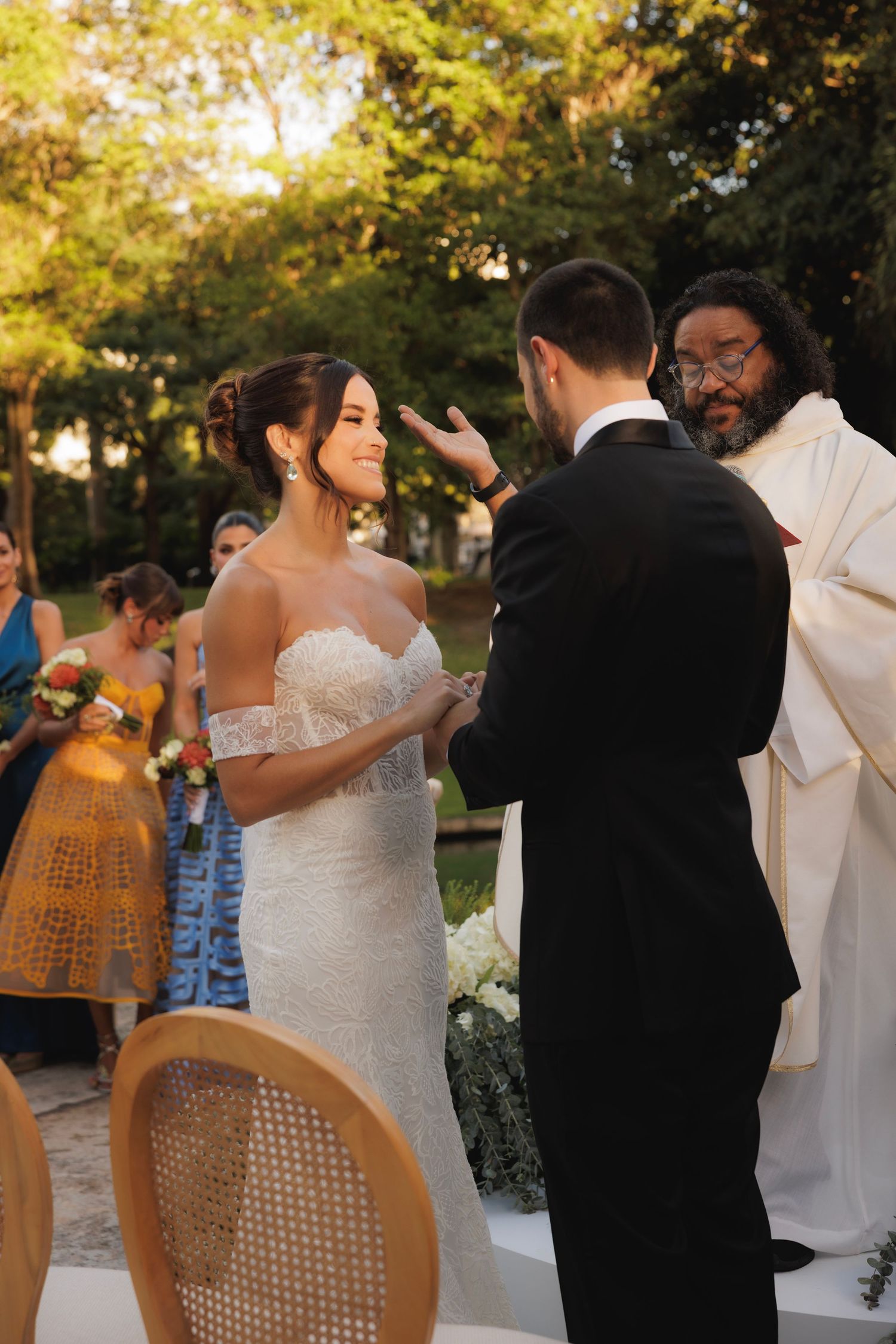 Wedding party dances outdoors with guests in yellow and blue attire.