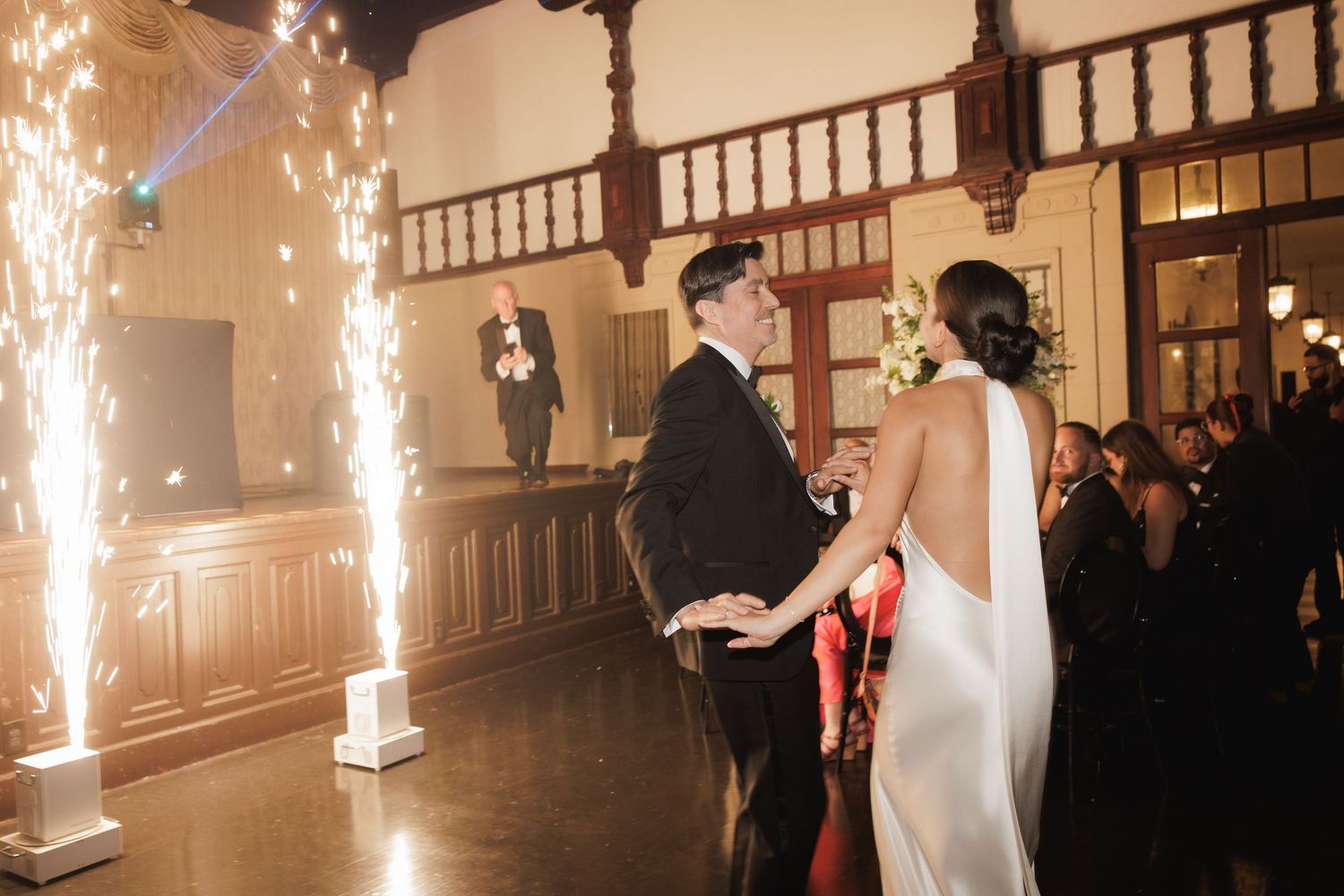 Sparklers create a magical atmosphere as a couple celebrates during their first dance at an elegant indoor wedding reception.