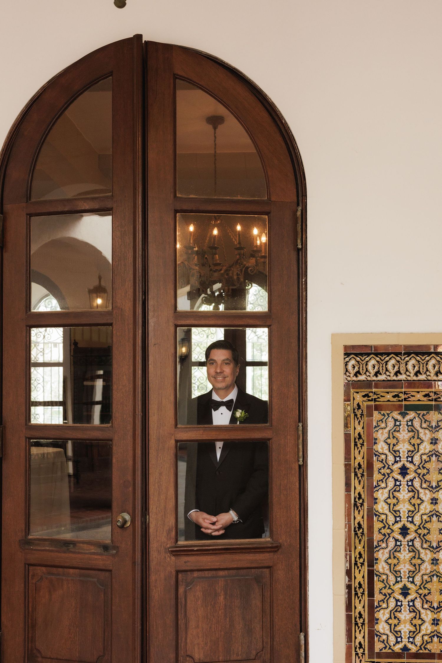 View through arched wooden doors showing glimpses of an elegant wedding venue interior.