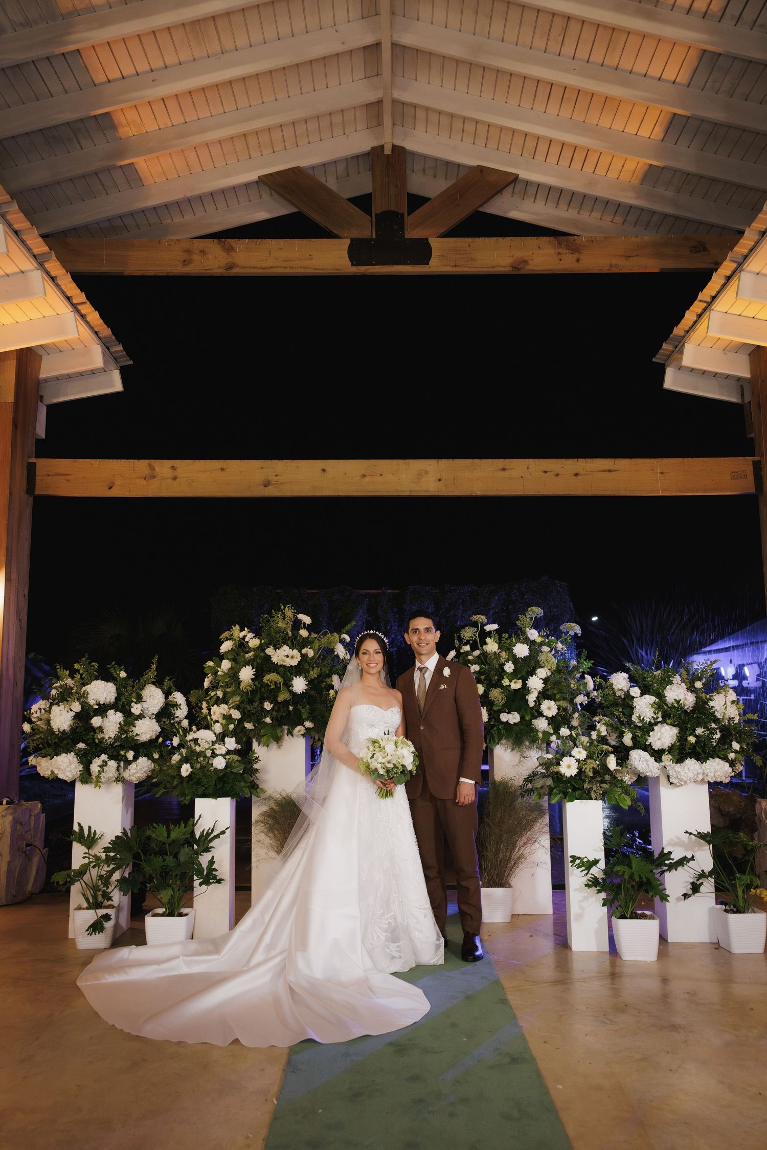 Elegant bridal portraits in a rustic venue with white floral arrangements and exposed wooden beams.