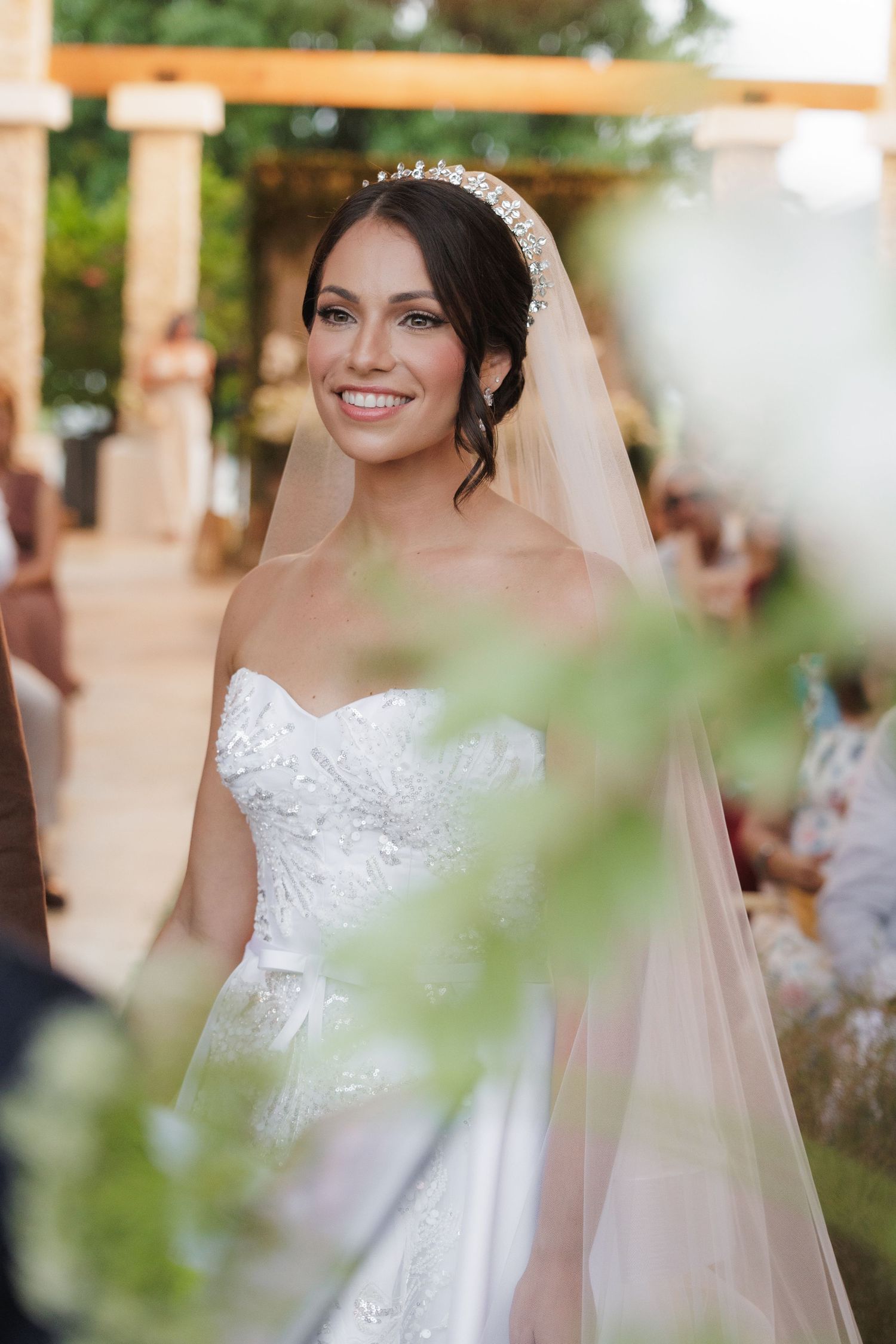 Elegant wedding dress details with lace bodice and flowing veil in natural outdoor lighting.