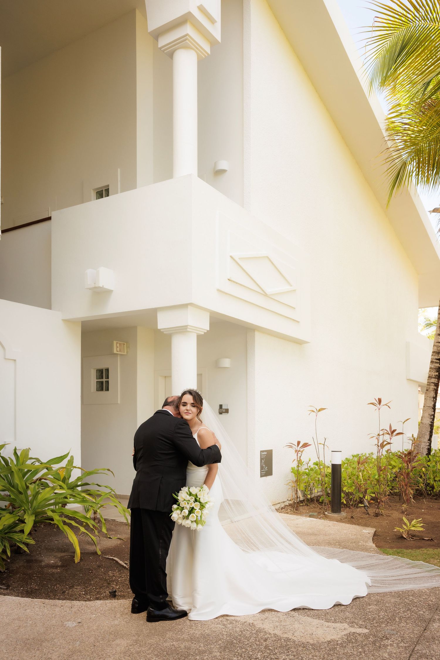 A romantic sequence of wedding photos captured outside a white stucco building with tropical palm landscaping.