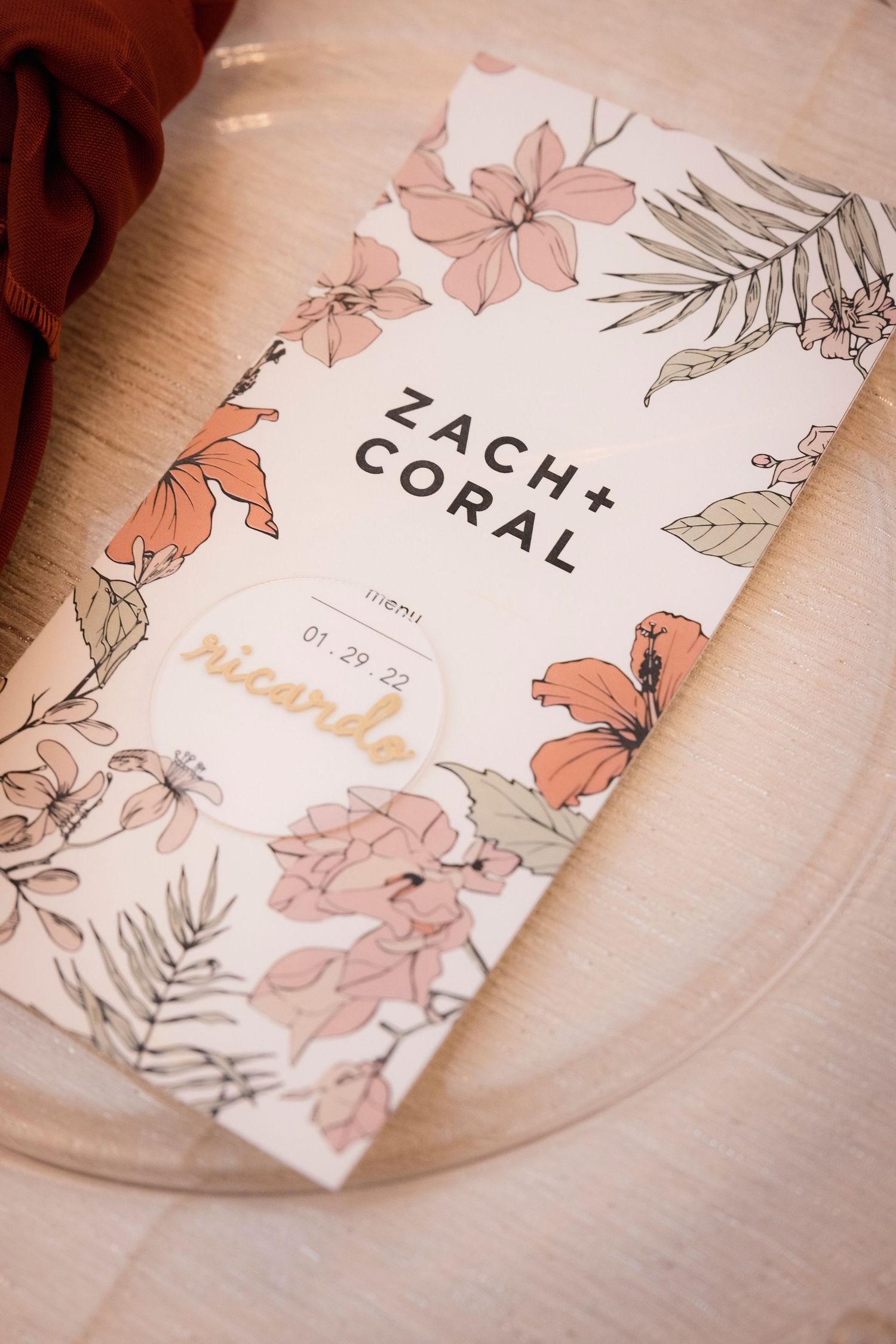 A romantic wedding invitation design with coral and pink floral illustrations and 'Zach + Coral' text on light background.