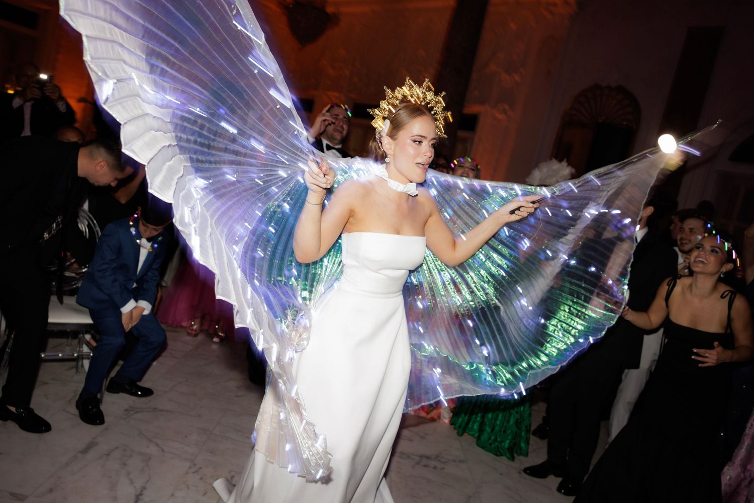 A dancer performs with flowing iridescent fabric wings creating an ethereal effect during a stage performance.