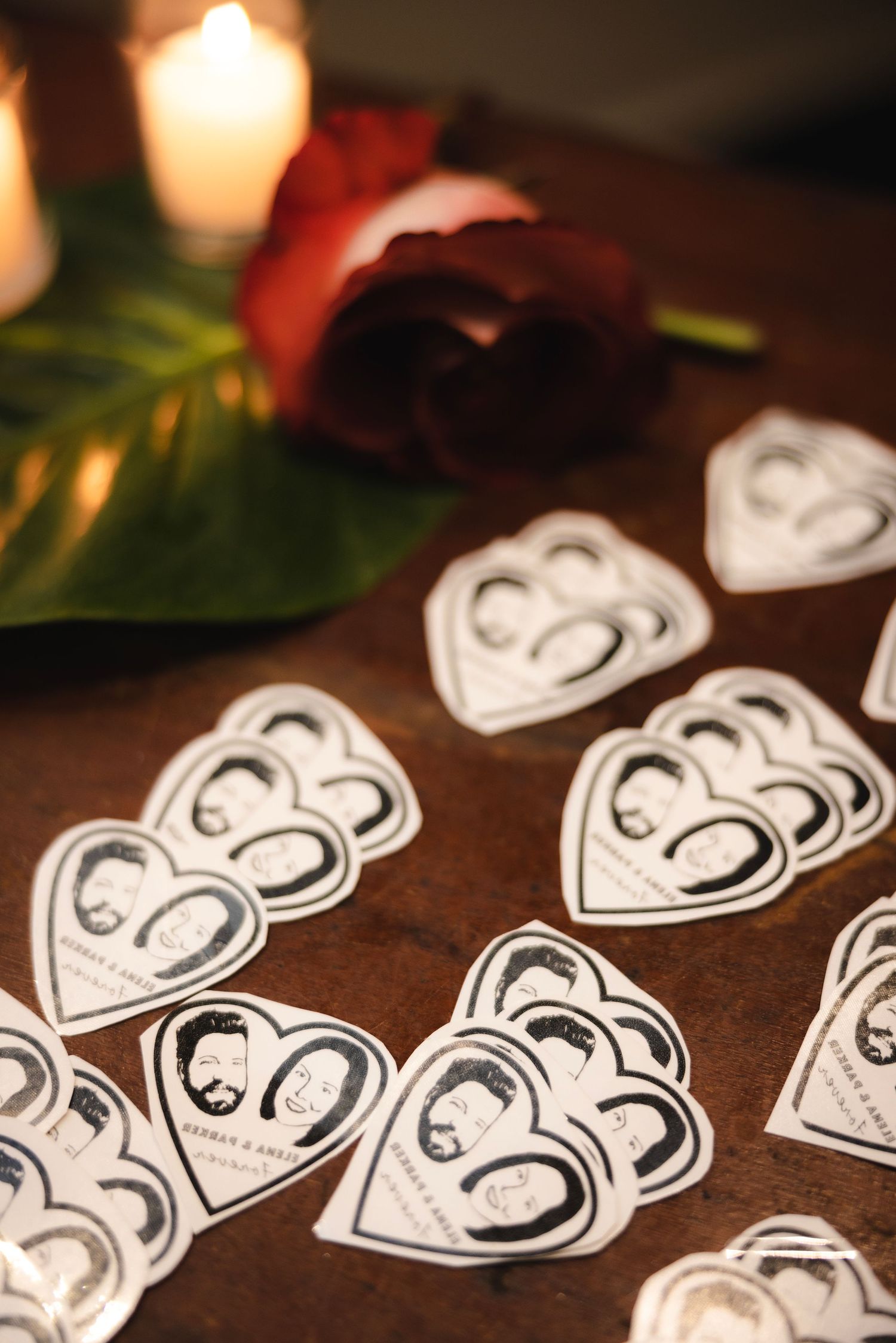 White heart-shaped paper cutouts arranged in a row with candlelight illumination creating a romantic atmosphere.