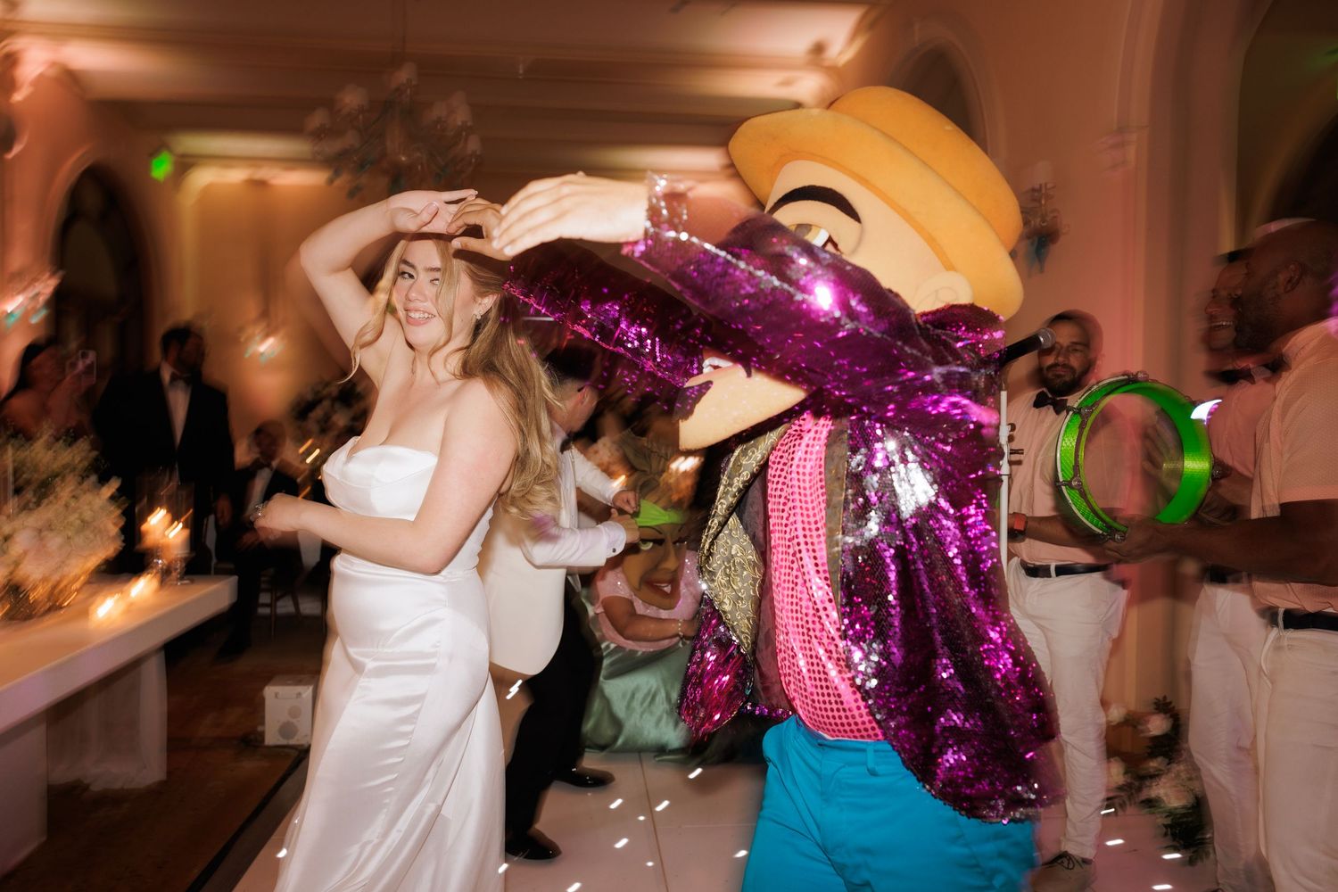 Wedding reception dance floor filled with guests dancing and having fun under chandelier lighting.