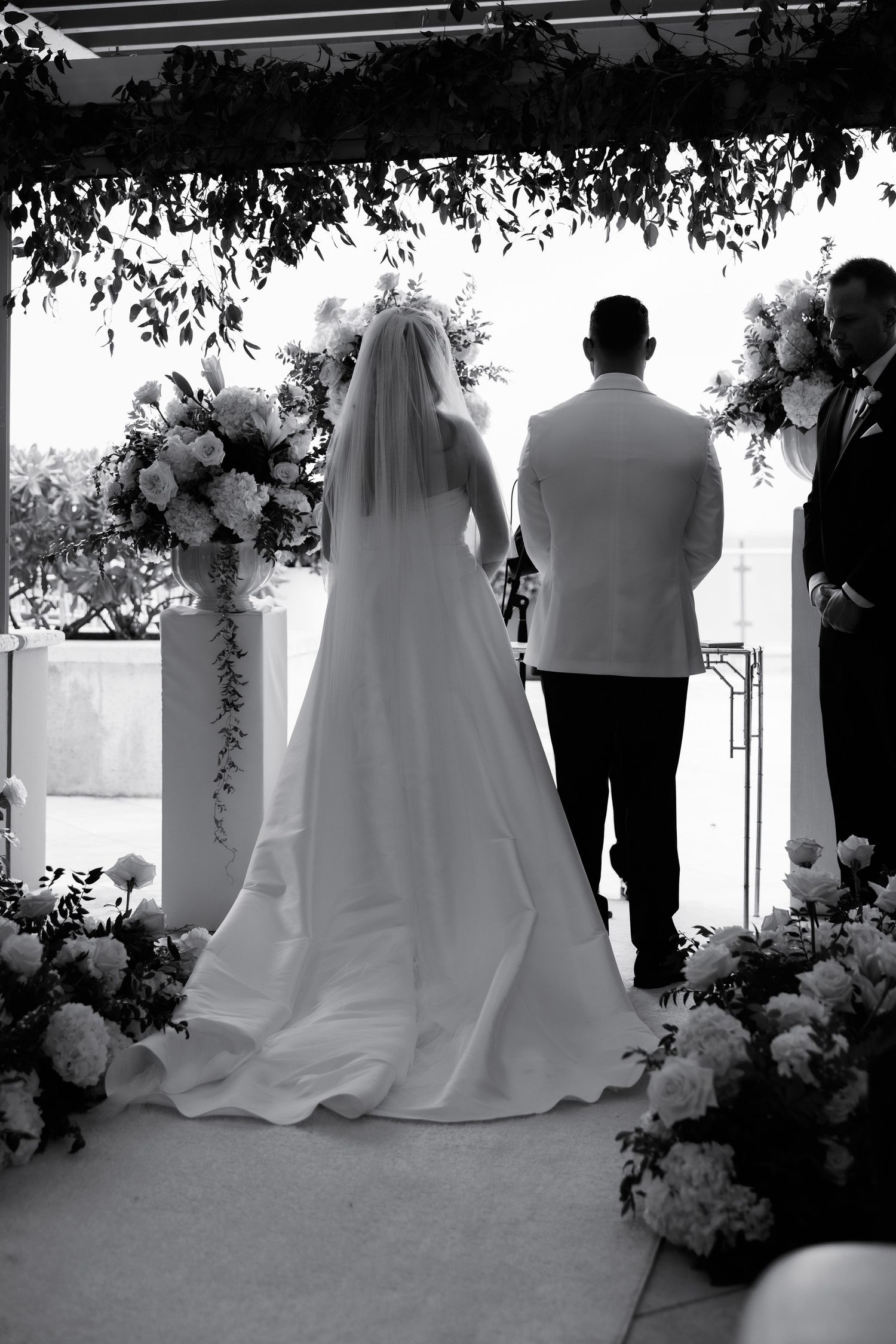 Black and white silhouette of wedding ceremony with floral arrangements and guests.
