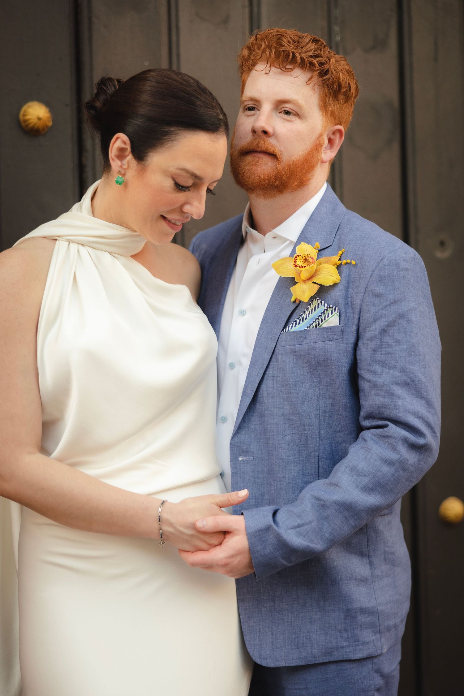 A romantic wedding couple embraces in a series of tender moments wearing white dress and blue suit with yellow boutonniere.