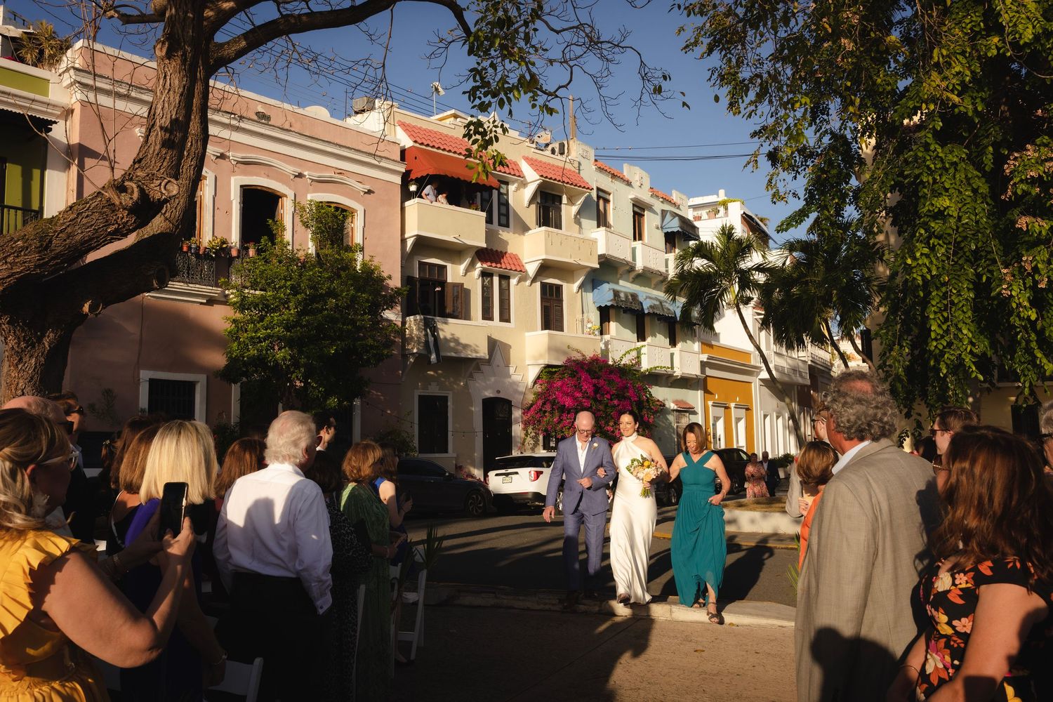 Street festival attendees enjoying food and activities along a historic street lined with colorful buildings.