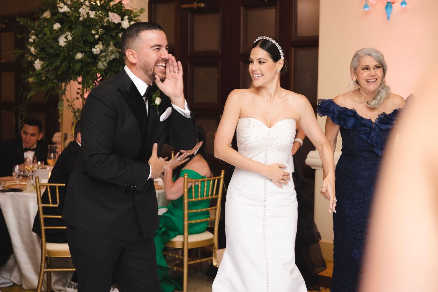 Wedding guests and newlyweds share an emotional moment during reception celebrations at an elegant venue.
