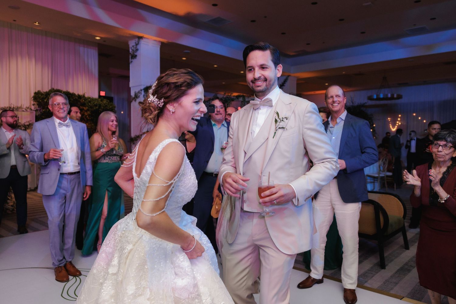 People dancing and celebrating at an elegant wedding reception in a room with warm lighting and decorative details.