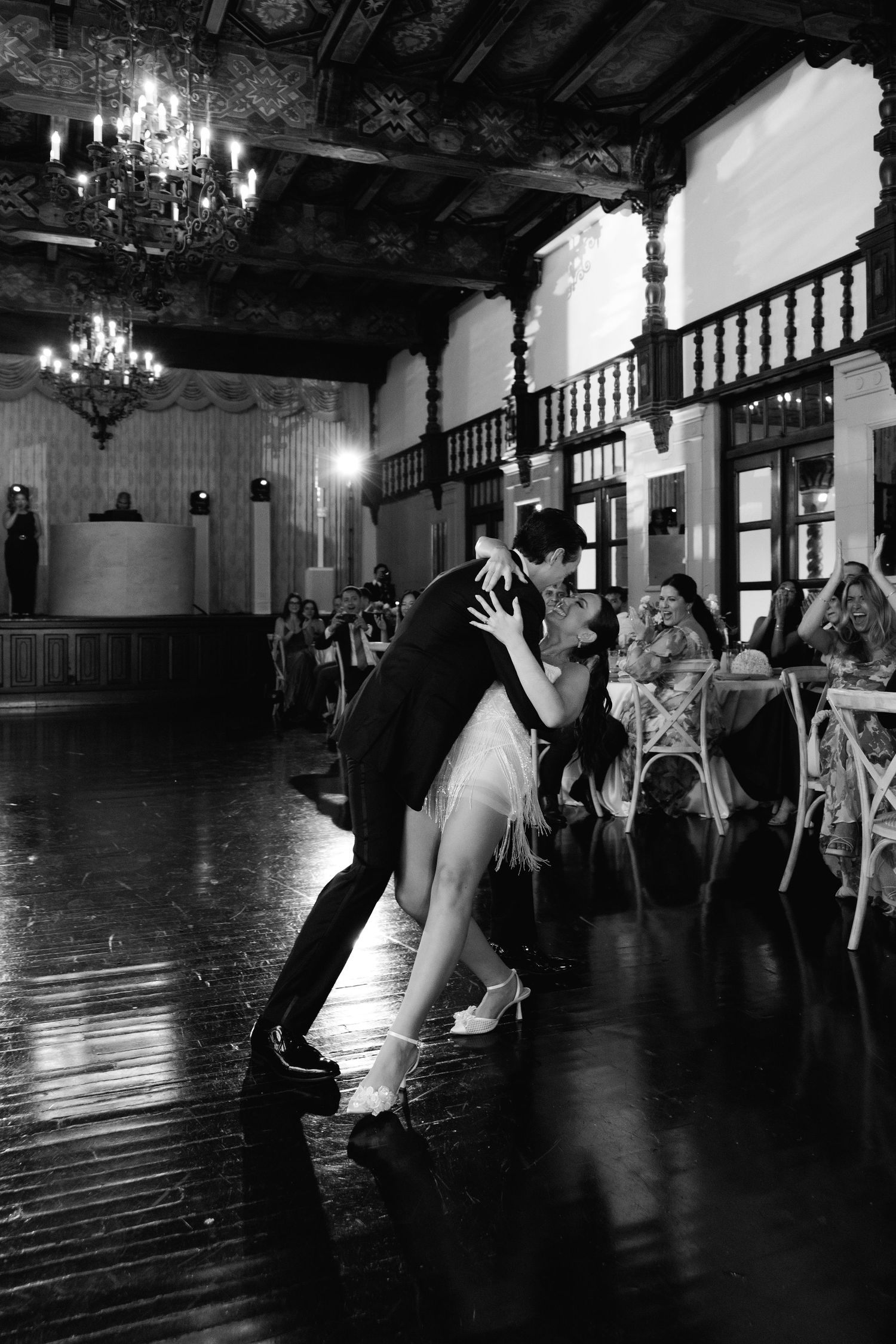 Dramatic black and white dance sequence showing silhouettes in an elegant ballroom with chandeliers.