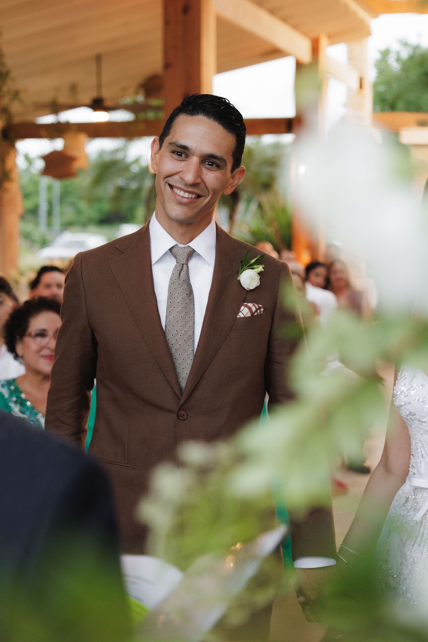 A wedding ceremony moment captured under a wooden pavilion with elegant decor and natural lighting.