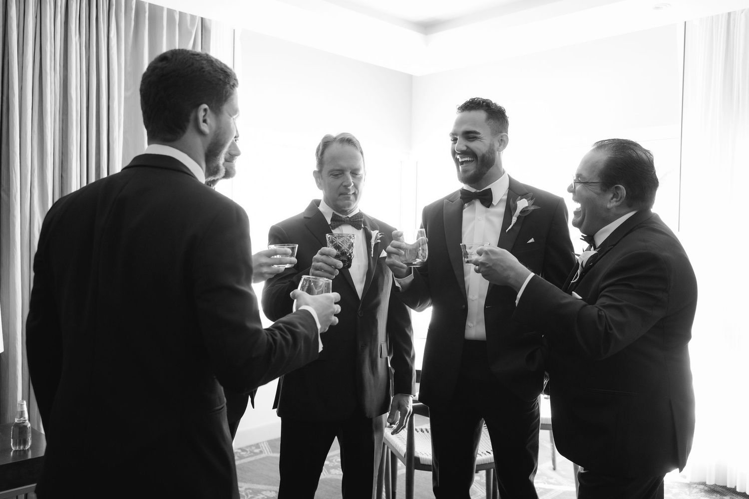 A black and white photo showing people in suits interacting and conversing at a gathering.