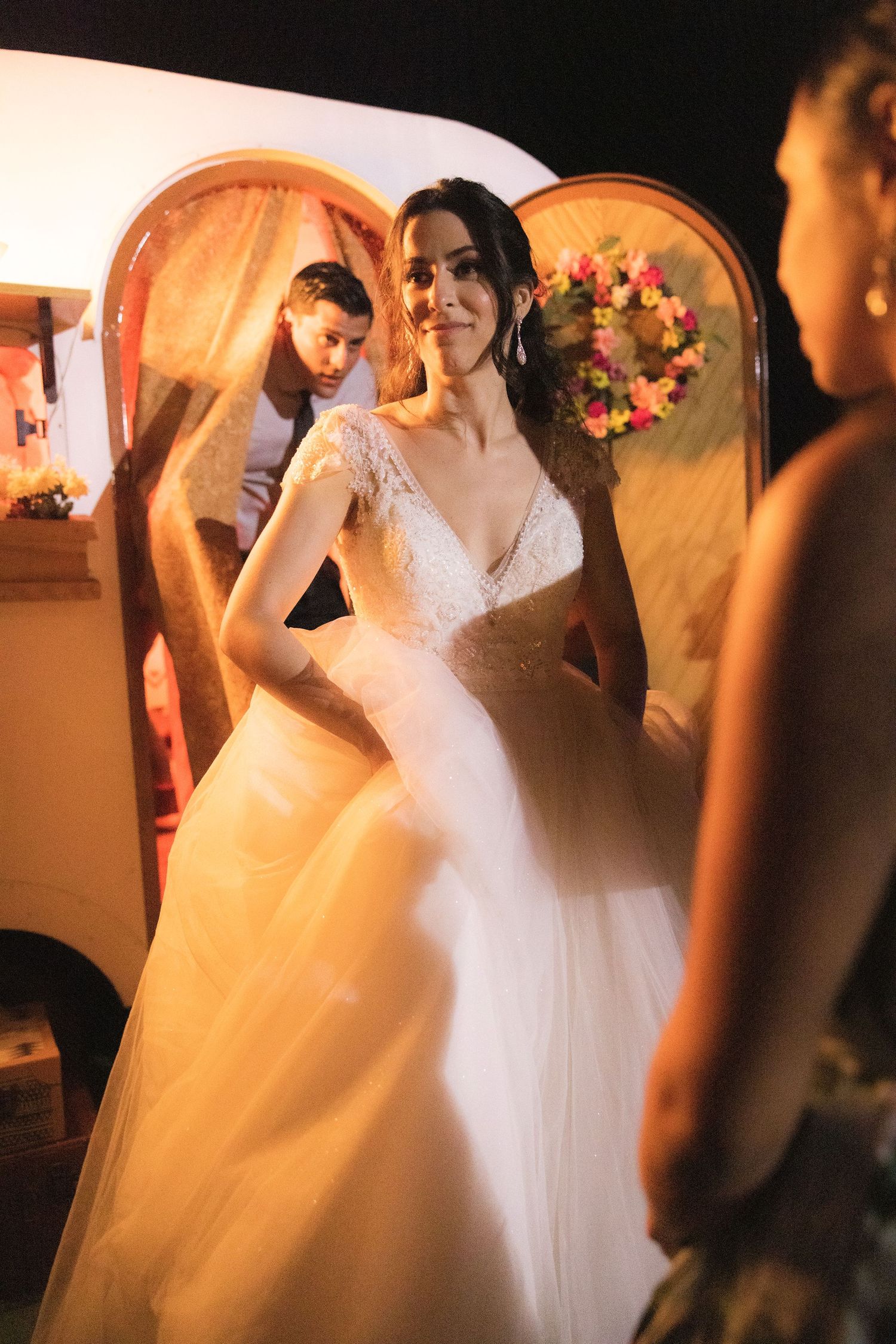 A bride twirls in her flowing white wedding dress amidst warm ambient lighting during a reception.
