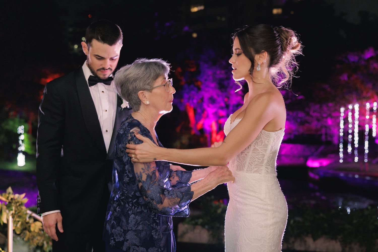 Couples enjoying a festive dance celebration with purple and pink lighting at an elegant evening party.
