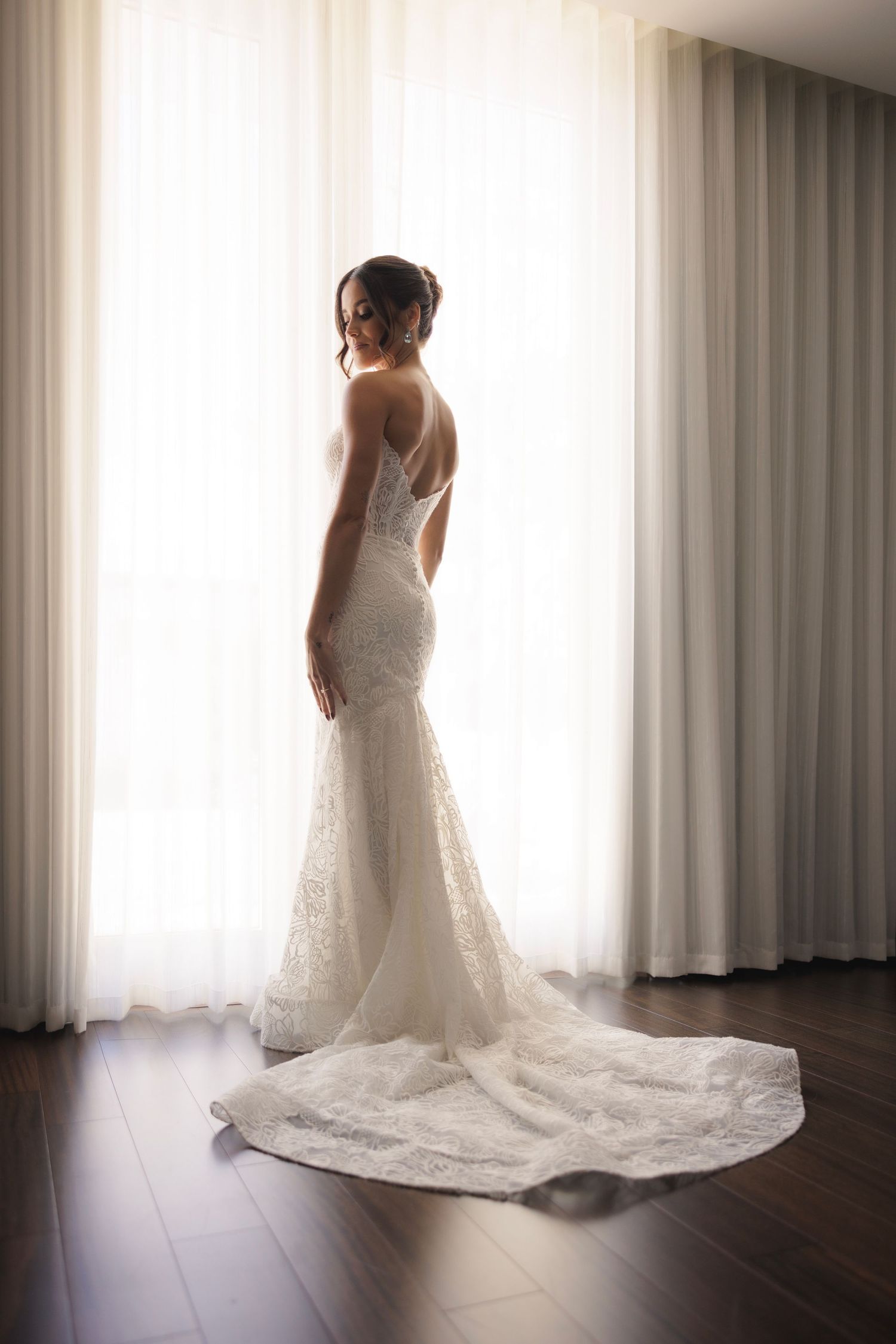 Elegant white wedding dress with long train photographed in sequence against natural window light.