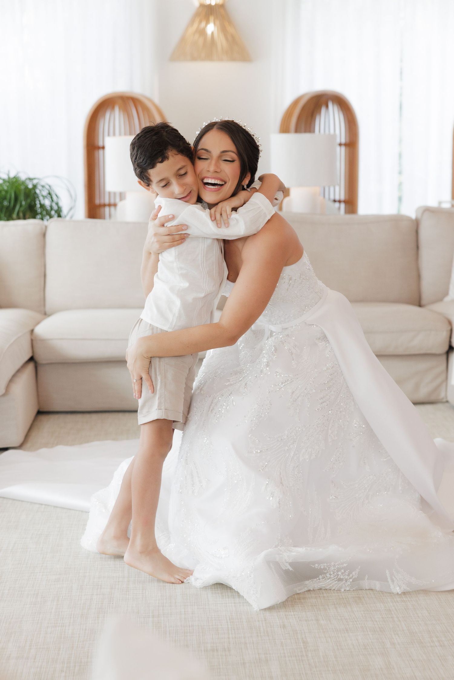 A joyful moment captured in white as two people embrace and play on a light colored couch in a bright room.