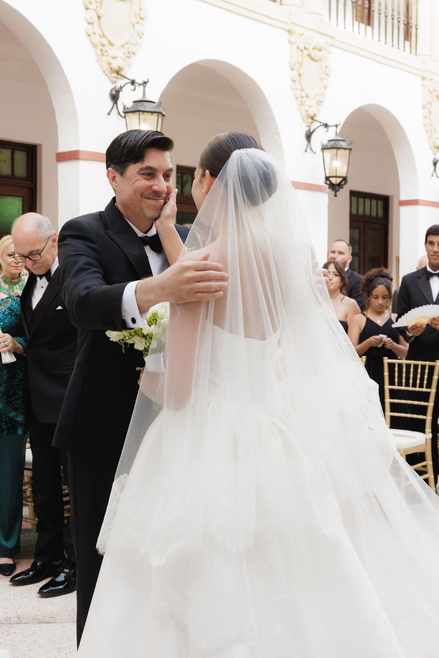 Wedding ceremony moments captured under white archways with classic architectural details.