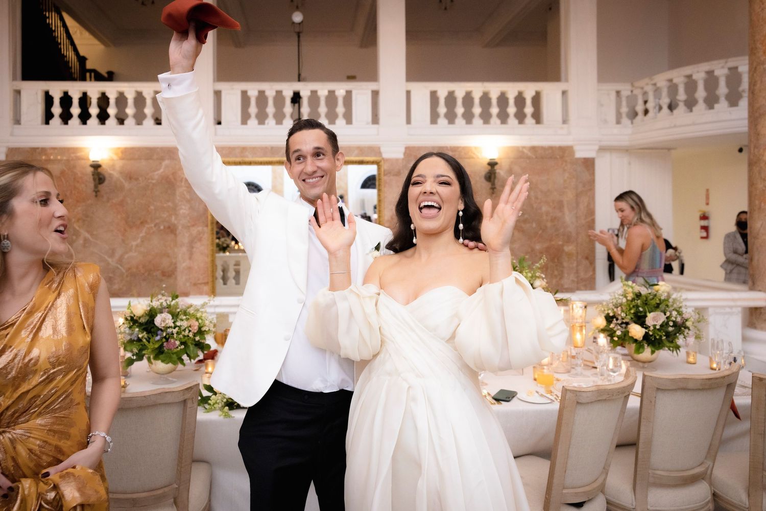 Joyous dance celebration during a wedding reception in an elegant ballroom with marble columns.