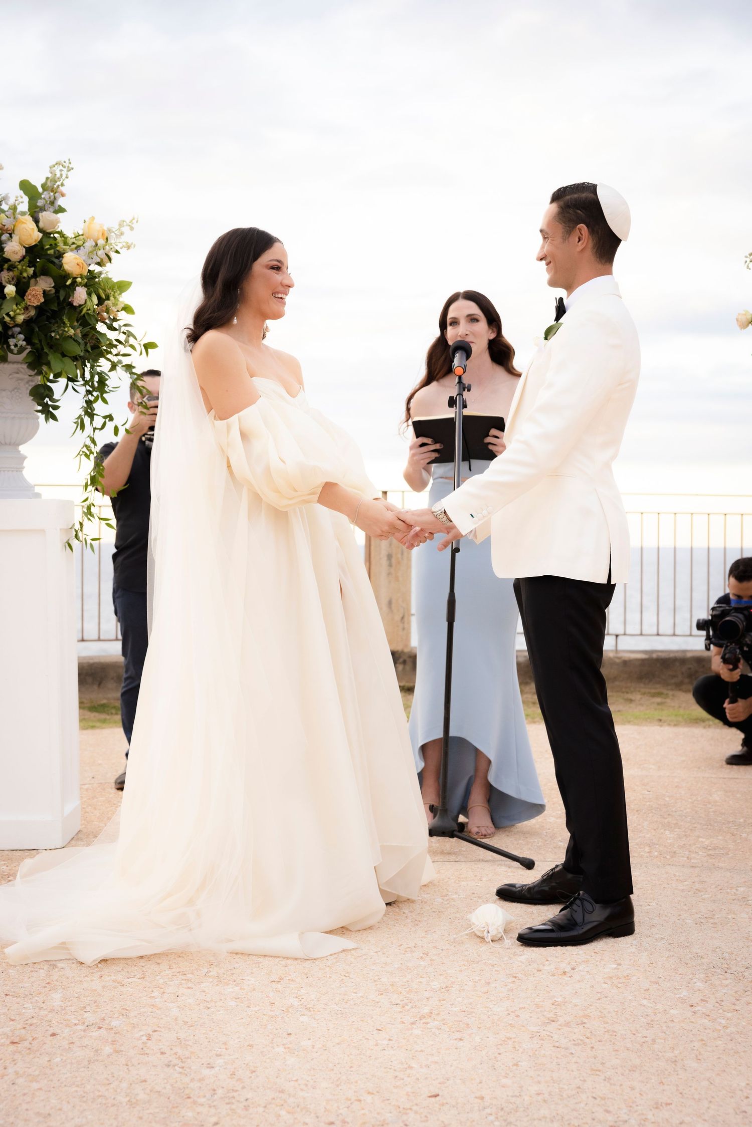 Wedding couple shares intimate moments during their ceremony against a scenic overlook backdrop.