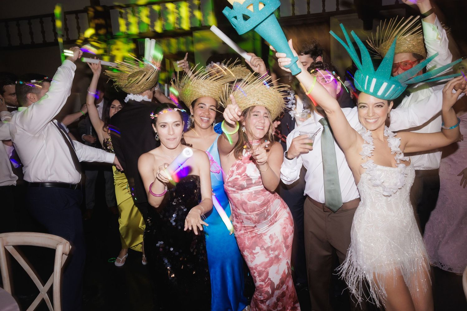 Wedding guests dance and celebrate on a lively dance floor with dynamic lighting and energetic movements.