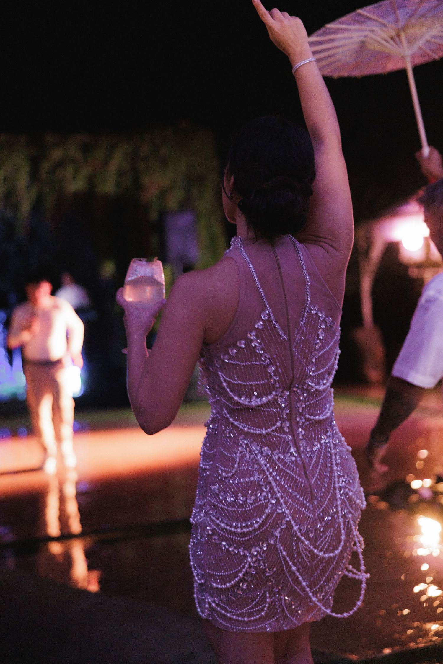Close-up of a beaded dress detail glowing under purple event lighting.